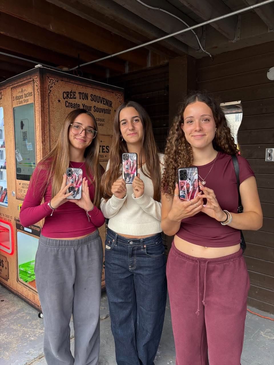 Trois amies tenant chacune leur coque avec une photo de groupe